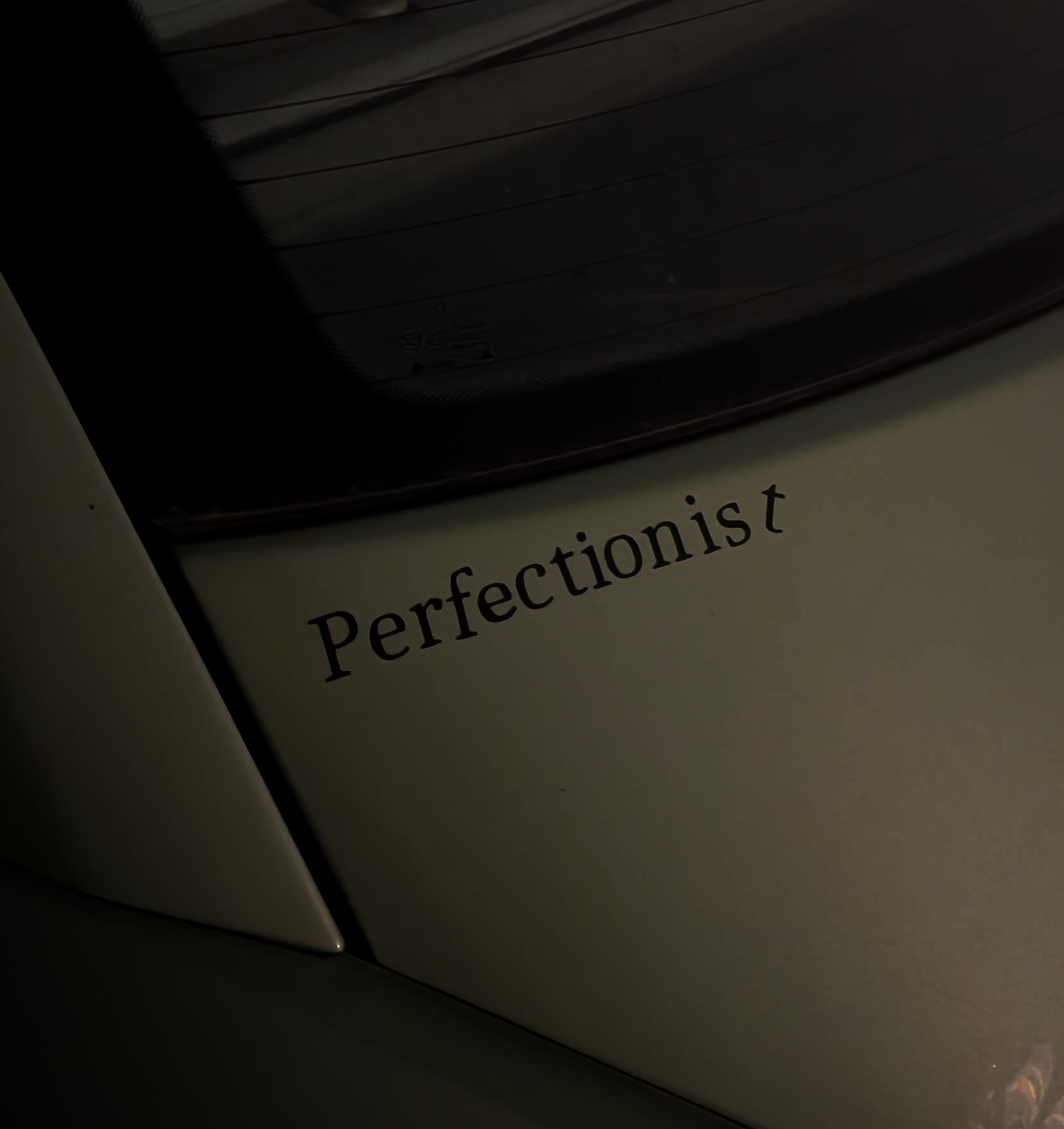 Car interior with 'Perfectionist' decal on a dark background
