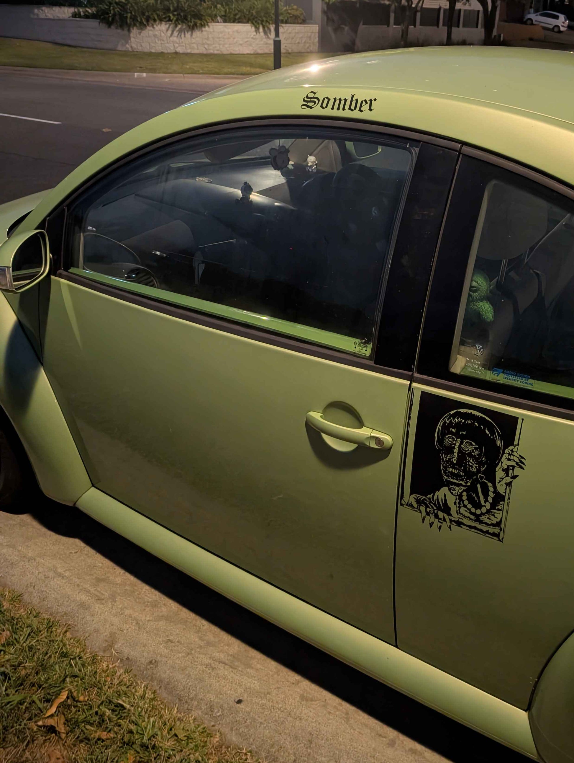 Green car with a sticker on the door at night